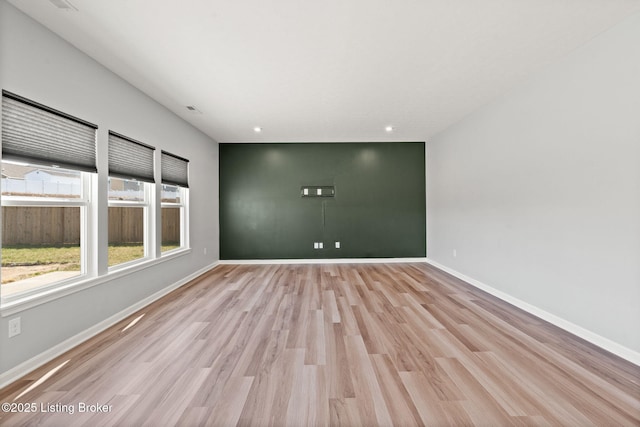 spare room featuring recessed lighting, light wood-style floors, and baseboards