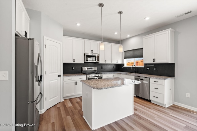 kitchen with stainless steel appliances, visible vents, light wood-style flooring, and decorative backsplash