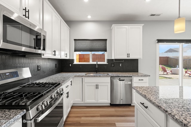 kitchen with visible vents, light wood-type flooring, stainless steel appliances, white cabinetry, and a sink