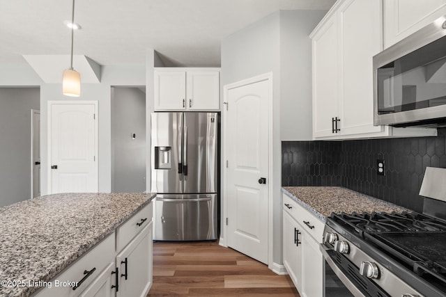 kitchen featuring light stone counters, white cabinetry, stainless steel appliances, and light wood-style floors