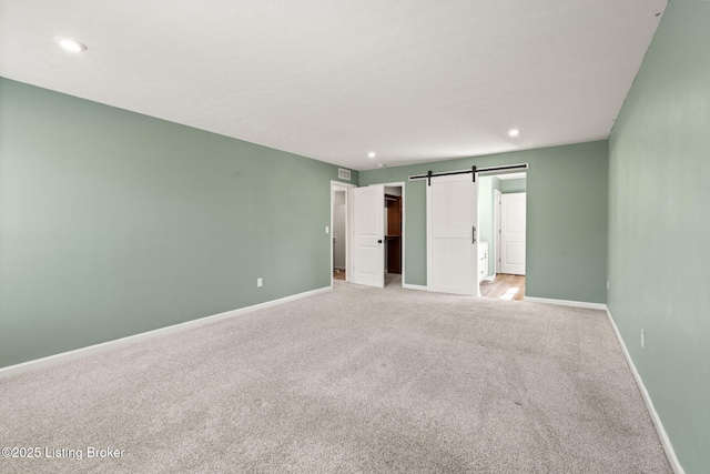 unfurnished bedroom featuring visible vents, baseboards, light colored carpet, a barn door, and recessed lighting