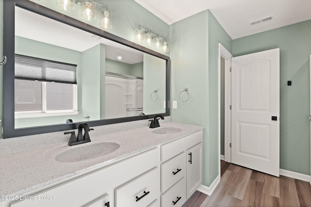 full bath featuring a sink, visible vents, wood finished floors, and double vanity