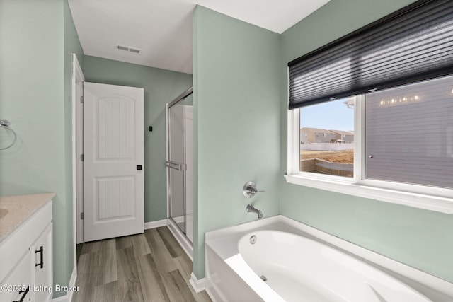 full bath featuring visible vents, a stall shower, wood finished floors, a bath, and vanity