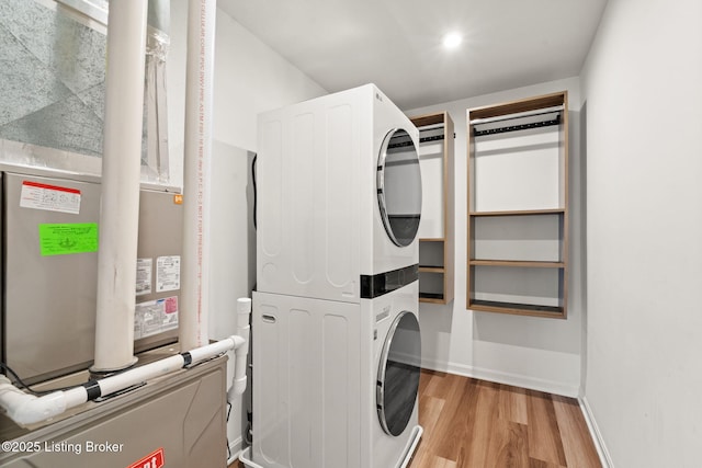 laundry area featuring stacked washer / drying machine, baseboards, light wood-style flooring, and laundry area