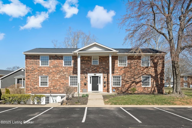 view of front of house featuring brick siding, a front lawn, and uncovered parking