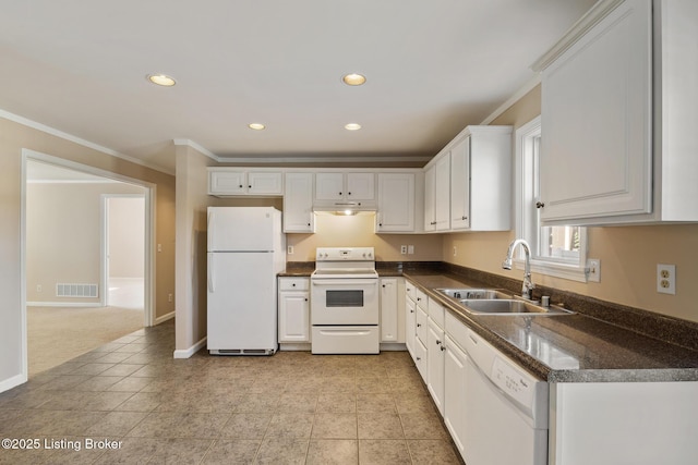 kitchen with white appliances, dark countertops, visible vents, and a sink