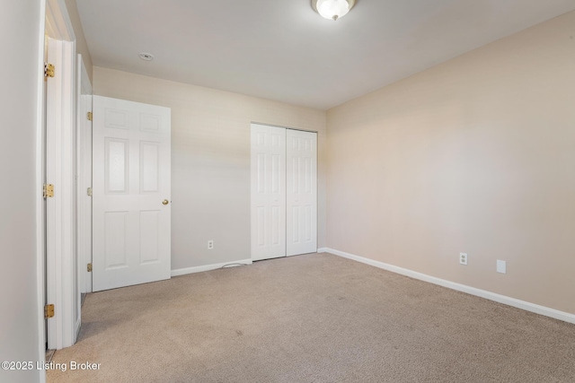 unfurnished bedroom featuring a closet, baseboards, and carpet