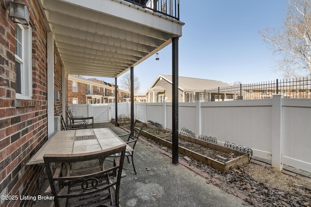 view of patio with outdoor dining area, a fenced backyard, and a garden