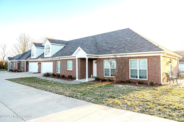 new england style home with a front lawn, brick siding, concrete driveway, and an attached garage