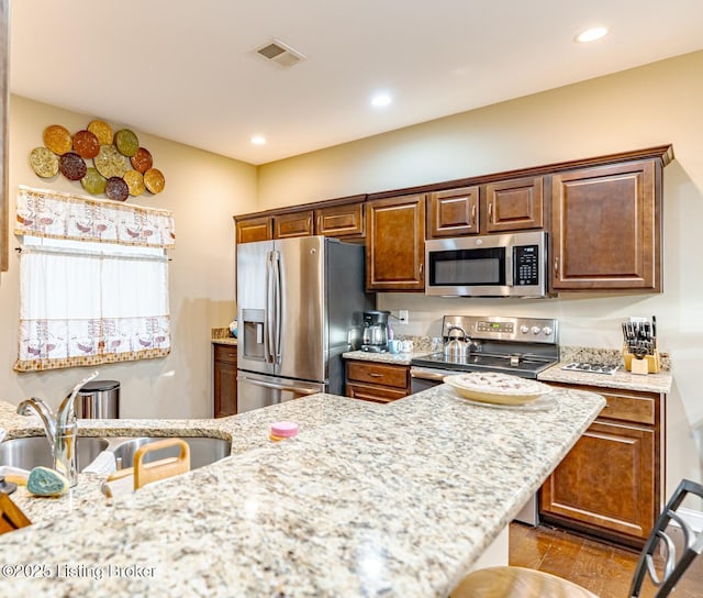 kitchen featuring visible vents, light stone countertops, recessed lighting, appliances with stainless steel finishes, and wood finished floors