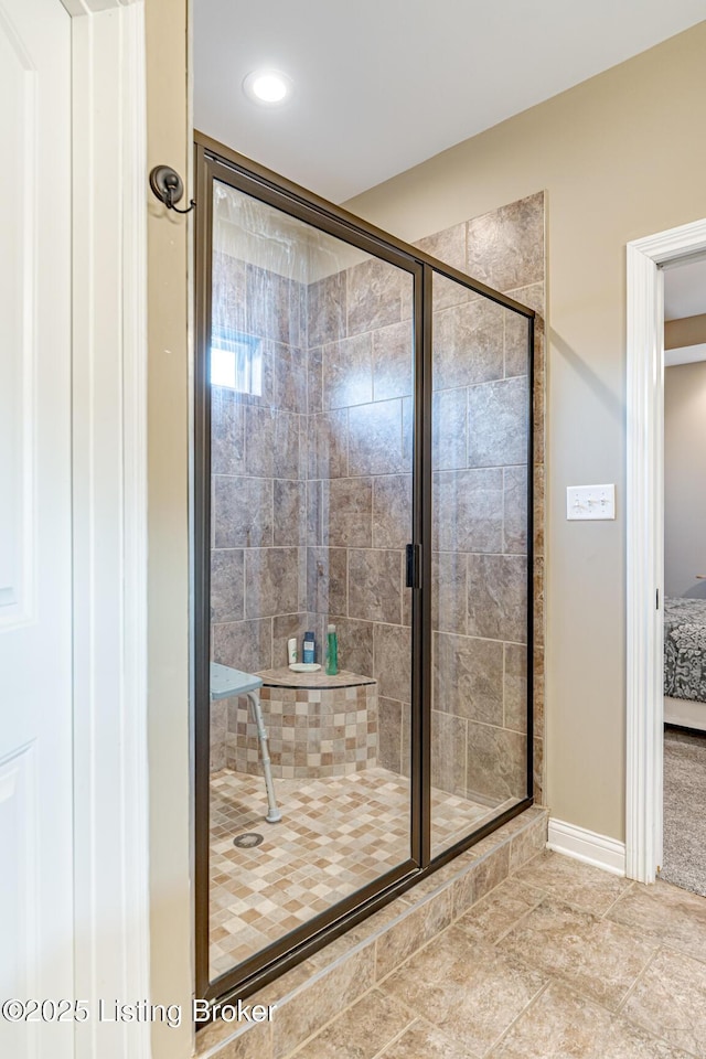 full bathroom with connected bathroom, baseboards, and a shower stall