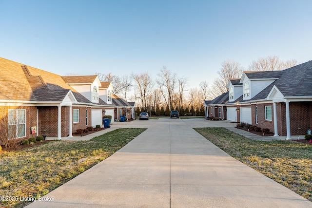 view of side of property featuring concrete driveway, a yard, and brick siding