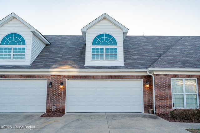 view of front of home featuring brick siding, driveway, and a shingled roof