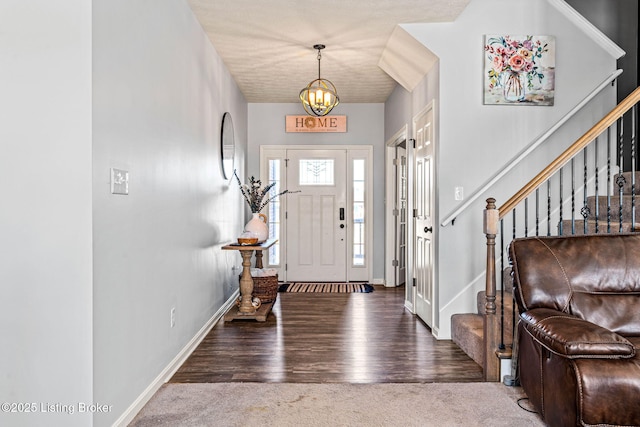 carpeted foyer entrance featuring a notable chandelier, stairs, baseboards, and wood finished floors