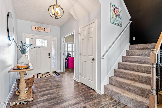 entrance foyer featuring baseboards, a notable chandelier, wood finished floors, and stairs