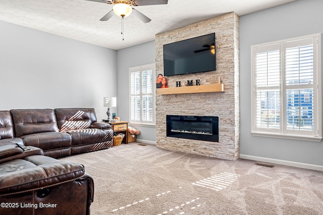 living room with a fireplace, a ceiling fan, carpet, and a textured ceiling