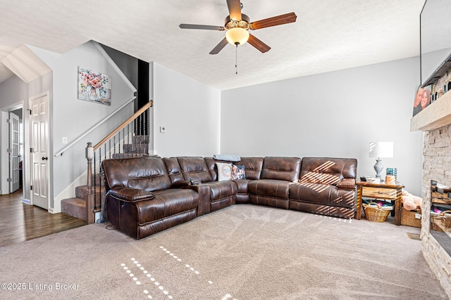 living area featuring a ceiling fan, a textured ceiling, stairway, carpet floors, and a fireplace