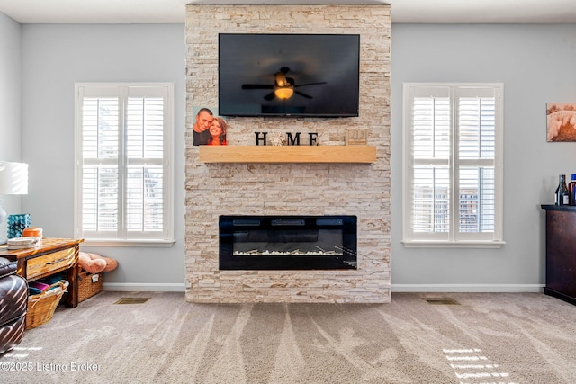 living room featuring a wealth of natural light, visible vents, carpet, and a fireplace