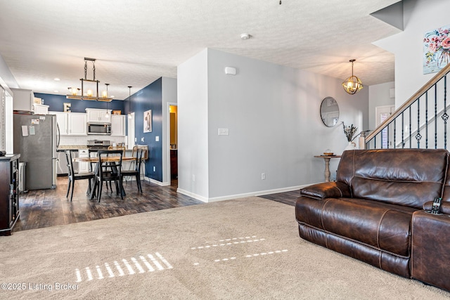 living room with baseboards, dark wood finished floors, stairs, a textured ceiling, and a chandelier