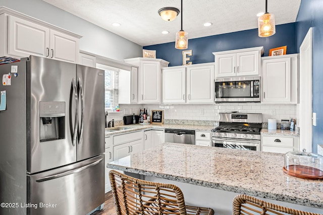 kitchen with white cabinets, decorative light fixtures, tasteful backsplash, and stainless steel appliances