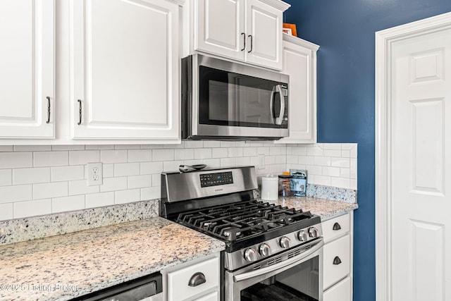 kitchen featuring stainless steel appliances, light stone countertops, tasteful backsplash, and white cabinetry