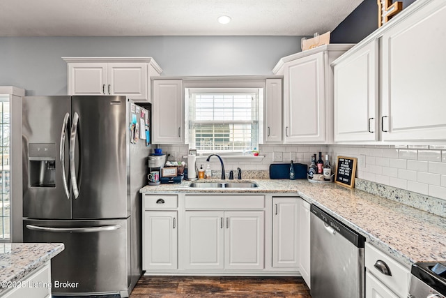 kitchen with a sink, stainless steel appliances, tasteful backsplash, and white cabinetry