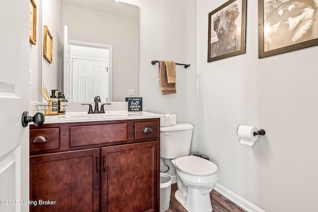 bathroom featuring vanity, toilet, wood finished floors, and baseboards