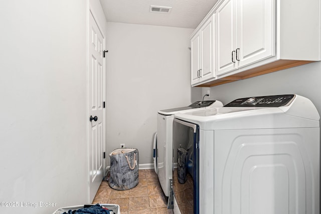 laundry room with baseboards, visible vents, washing machine and clothes dryer, cabinet space, and a textured ceiling