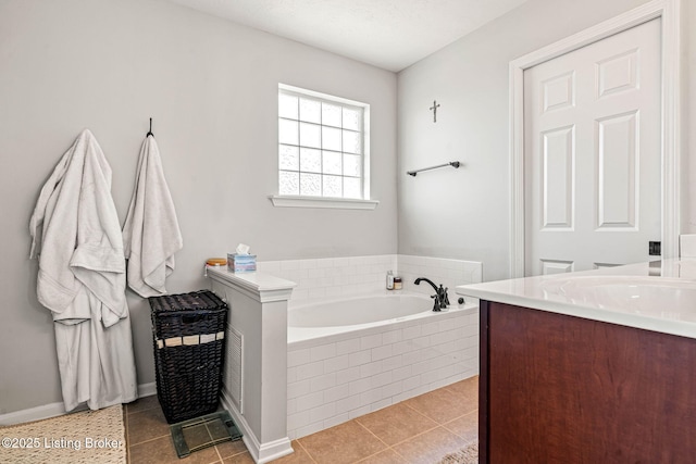 full bath featuring a garden tub, vanity, and tile patterned flooring