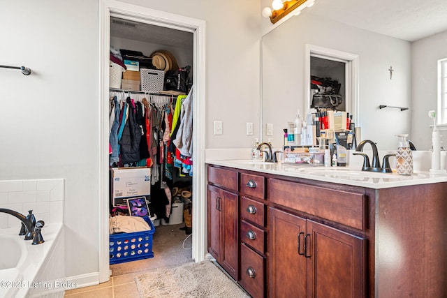 bathroom with a walk in closet, double vanity, a washtub, and a sink