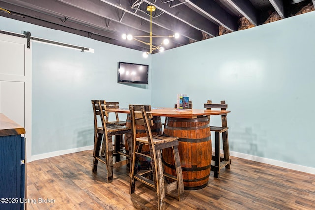 dining room with baseboards, a barn door, and wood finished floors