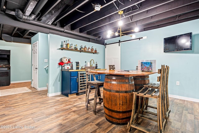 bar featuring wet bar, beverage cooler, light wood-style floors, and baseboards