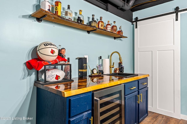 bar with a sink, wine cooler, a dry bar, a barn door, and dark wood-style flooring