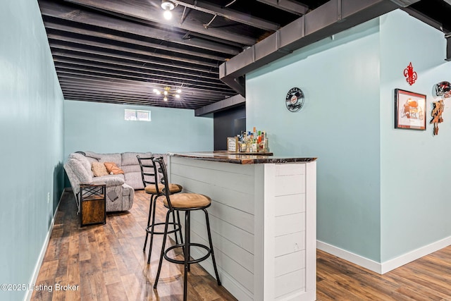 bar with visible vents, baseboards, a bar, and wood finished floors