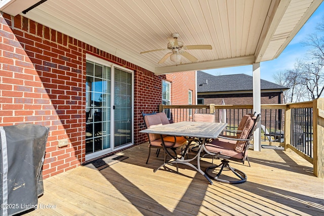 wooden terrace featuring area for grilling, outdoor dining space, and ceiling fan