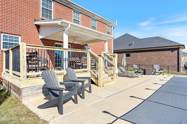 rear view of property featuring fence, brick siding, a ceiling fan, and a patio area