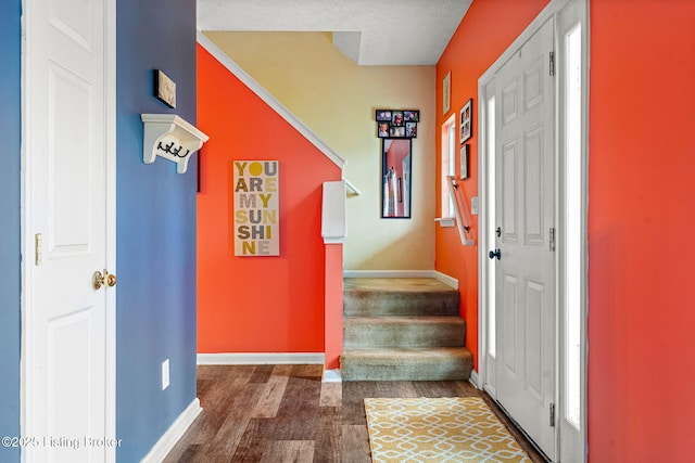 entryway with baseboards, wood finished floors, and stairs