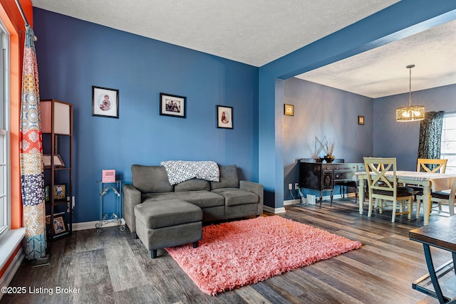 living room with baseboards, a textured ceiling, and wood finished floors