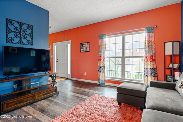 living area featuring wood finished floors, baseboards, and a textured ceiling