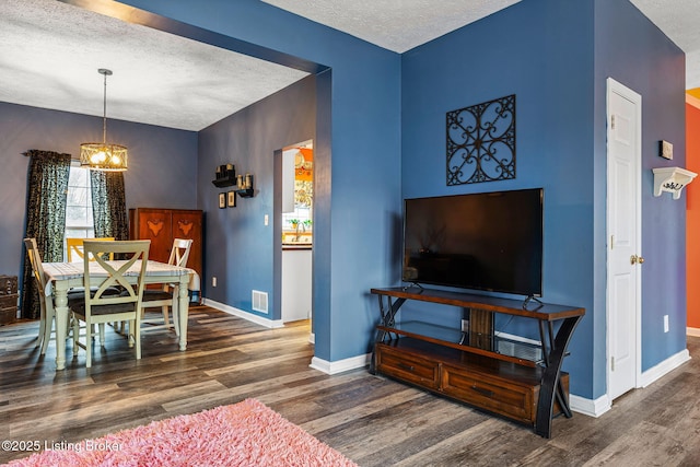 dining room featuring baseboards, wood finished floors, visible vents, and a textured ceiling