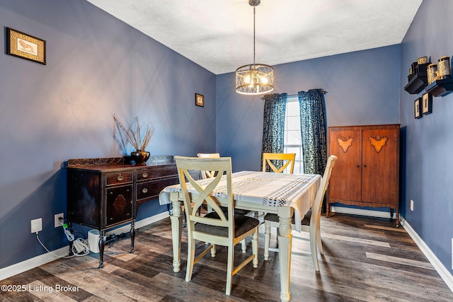 dining area with an inviting chandelier, wood finished floors, baseboards, and a textured ceiling