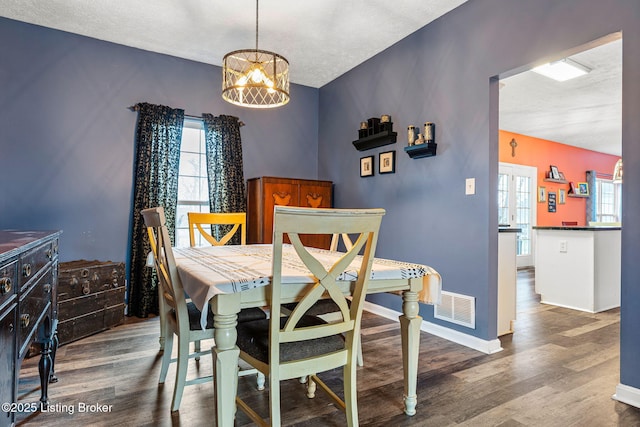 dining area featuring a notable chandelier, wood finished floors, visible vents, and baseboards