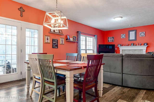 dining space with a notable chandelier, a textured ceiling, dark wood finished floors, and a fireplace