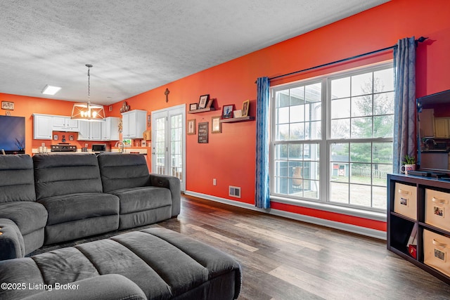 living area with a wealth of natural light, visible vents, dark wood finished floors, and a textured ceiling