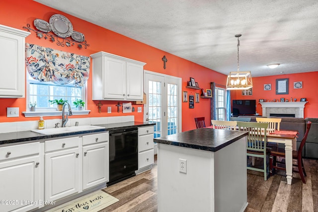 kitchen featuring a sink, plenty of natural light, dark countertops, and dishwasher