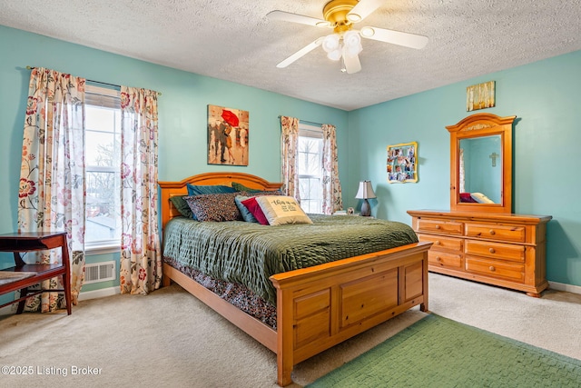 bedroom featuring a textured ceiling, carpet, visible vents, and ceiling fan