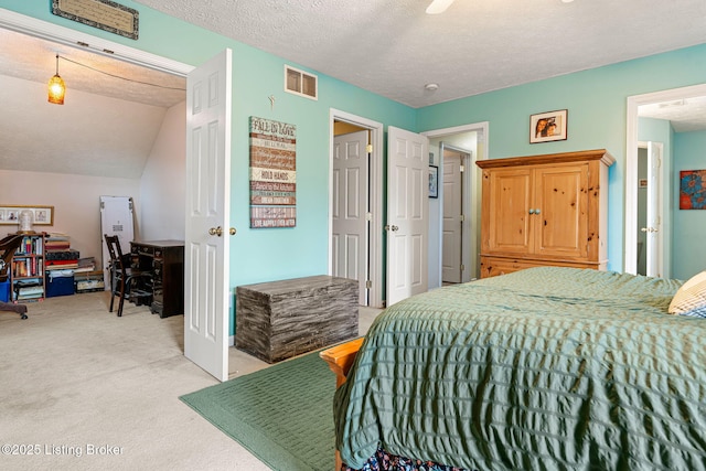 bedroom featuring visible vents, light colored carpet, a textured ceiling, and vaulted ceiling