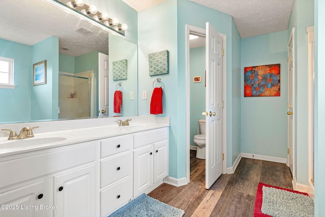 full bathroom with a shower stall, a textured ceiling, wood finished floors, and a sink