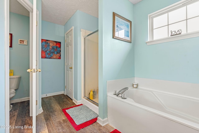 full bath featuring toilet, a textured ceiling, wood finished floors, a shower stall, and a bath