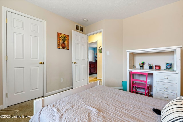 bedroom with visible vents, carpet flooring, a textured ceiling, and baseboards